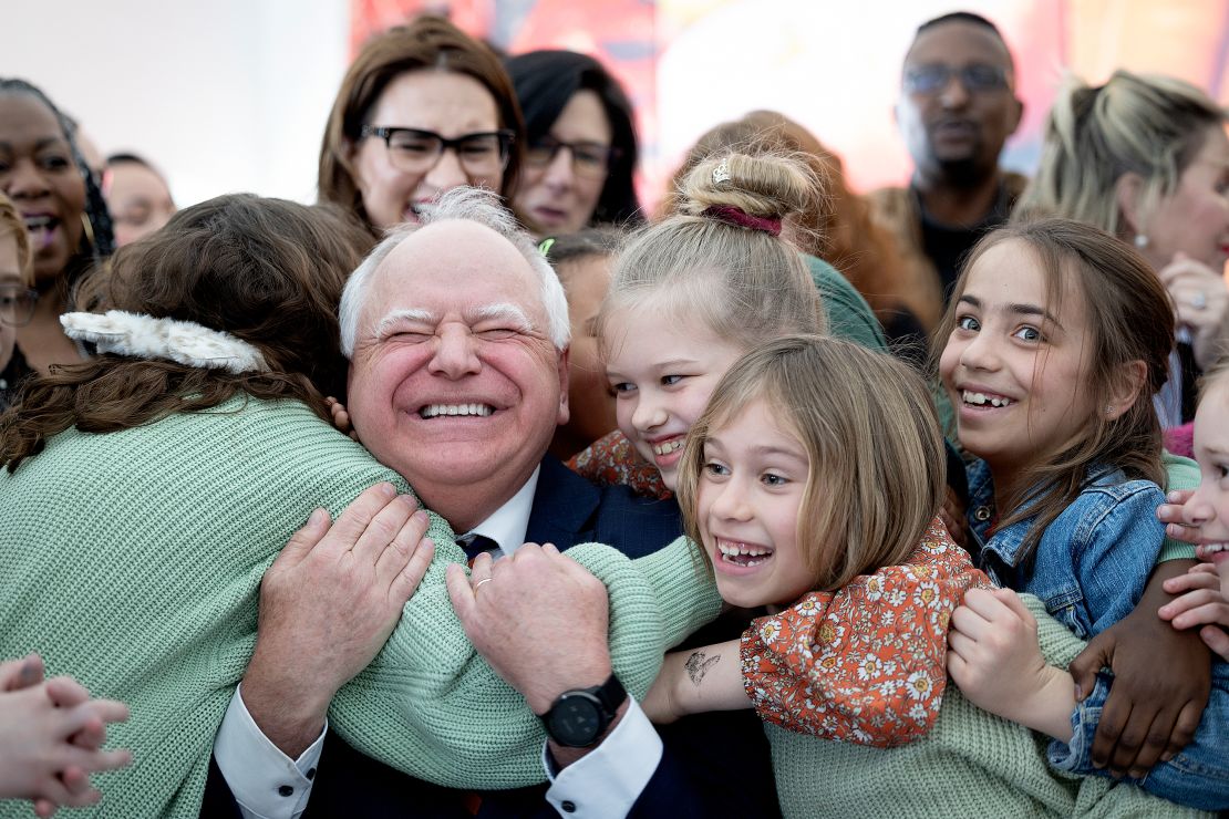 Tim Walz receives a hug from students at Webster Elementary in Minneapolis after he signed into law a bill that guarantees free school meals for every student in Minnesota's public and charter schools on March 17, 2023.